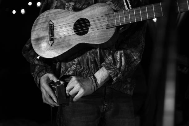 A young Mexican musician is plugging his jarana guitar to a speaker audio device during a concert. Concept of live music