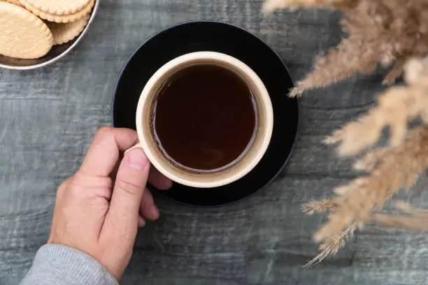 Photo of Hand holds mug of black coffee, drinking outdoors. Keep warm. Autumn mood.