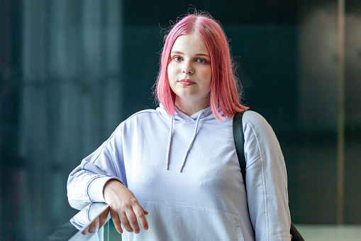 Outdoor portrait of an attractive young caucasian woman with pink hair