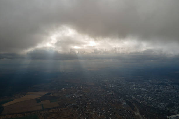 vue aérienne depuis la fenêtre de l’avion à haute altitude d’une ville lointaine recouverte d’une couche de smog brumeux mince et de nuages lointains le soir - ozone layer photos et images de collection