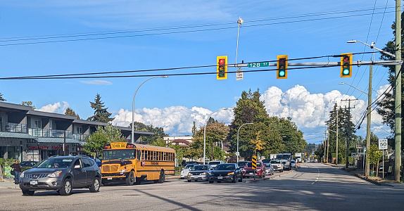Surrey, Canada - September 16, 2022: Traffic faces west on 88th Avenue at 128th Street. Residential and commercial buildings line the street. Mid-afternoon in summer in Metro Vancouver.