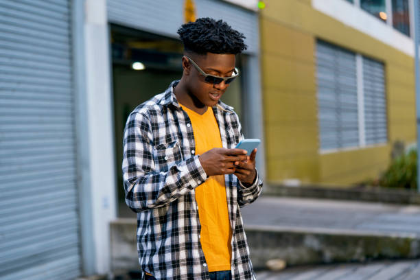 istock Young black man is using his mobile in the street while chatting with his friends 1425661011
