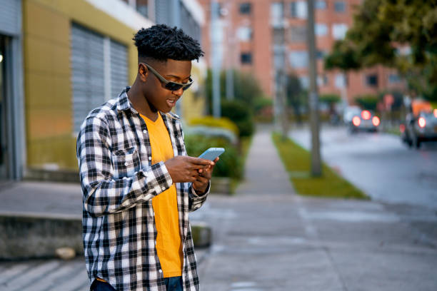 istock Young black man is using his mobile in the street while chatting with his friends 1425661088