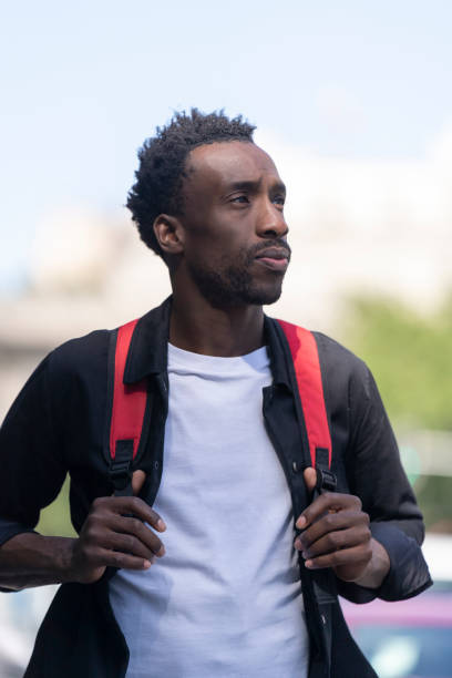 istock Portrait of a happy man walking with red backpack on his back 1425661951