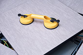 Yellow handheld device with vacuum suction cups for lifting floor panels