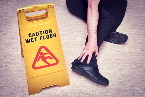 Falls and injuries on the wet floor. The sign on the plate with the text - caution wet floor