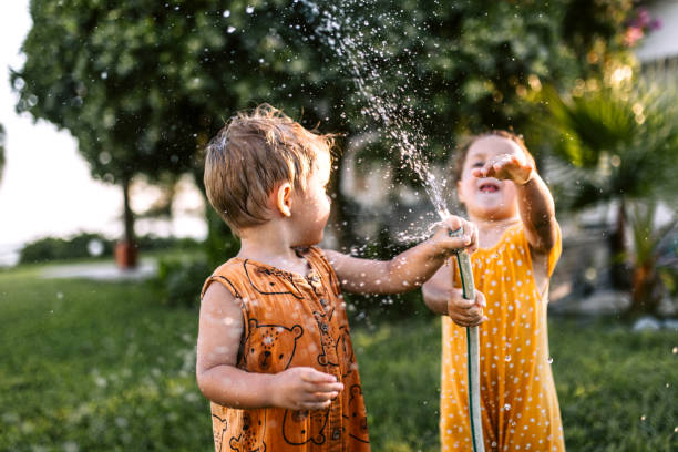 istock Children having fun spraying water with garden hose 1425688350