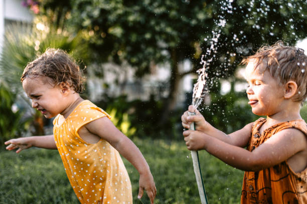 istock Children having fun spraying water with garden hose 1425688429