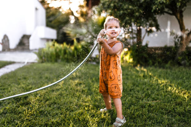 istock Little boy watering garden and having fun spraying water 1425688496