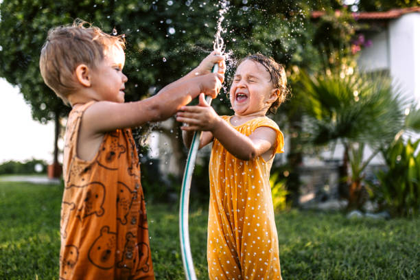 istock Children having fun spraying water with garden hose 1425688529