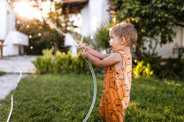 istock Little boy watering garden and having fun spraying water 1425688547