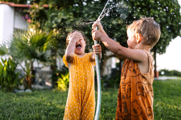 istock Children having fun spraying water with garden hose 1425688584