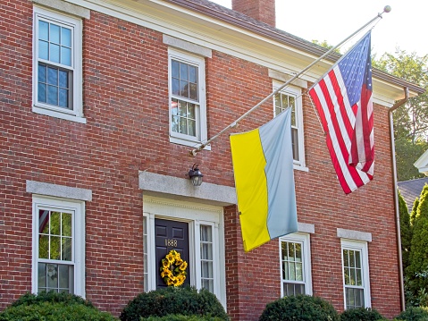 A brick colonial style home next to the Lexington battlefield memorial displays both the American and Ukrainian flags September 2022.