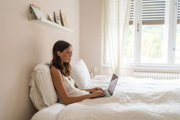 istock Young woman uses laptop in bed 1425694156