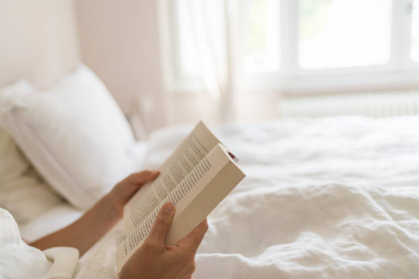 istock Young woman reads book in bed 1425694237