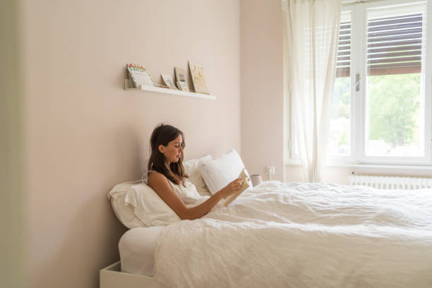 istock Young woman reads book in bed 1425694337