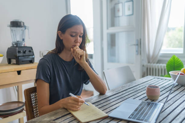 istock Young woman works on laptop at dining room table 1425694811