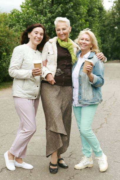 istock Three beautiful elderly women are walking in the park, having fun talking and drinking coffee. 1425696019