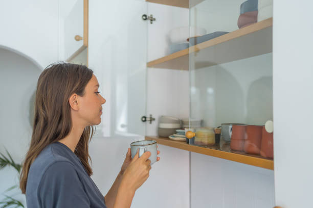 istock Young woman pics cup out of wall cupboard 1425699512