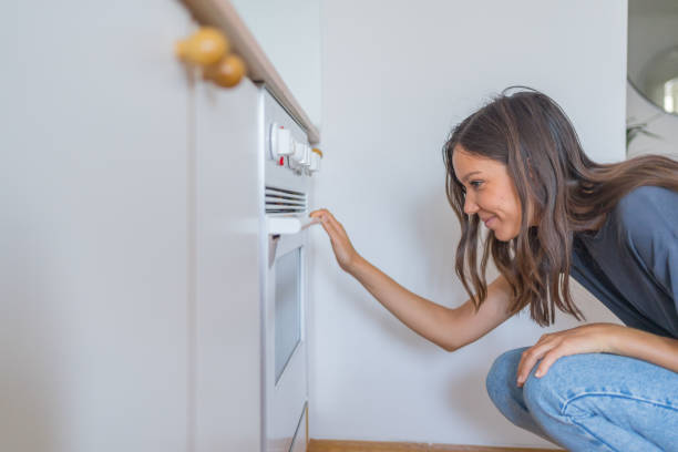 istock Young woman turns oven on in kitchen 1425699513