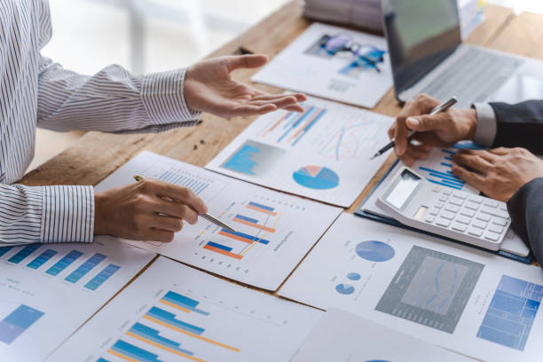 istock Business team of employees meeting, analyzing project document text, reports, marketing charts with sticky notes, planning work process, discussing papers, doing paperwork research. Close up of hands 1425699592