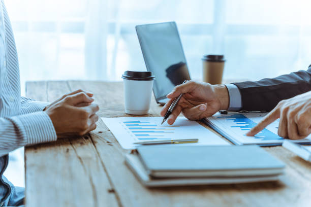 istock Business team of employees meeting, analyzing project document text, reports, marketing charts with sticky notes, planning work process, discussing papers, doing paperwork research. Close up of hands 1425699593