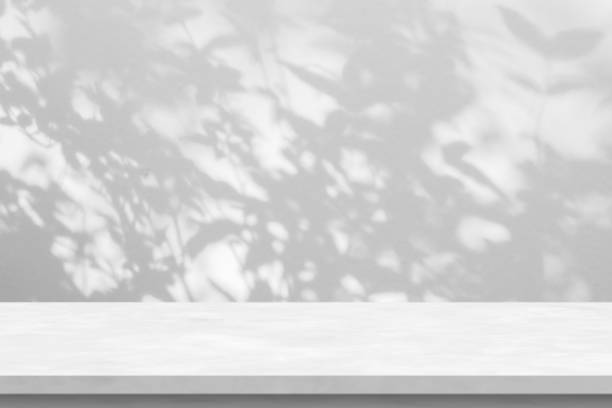 istock Marble table with tree shadow drop on white wall background for mockup product display 1425727536