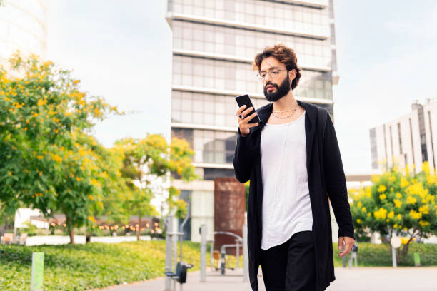 istock young man walking by the city using a mobile phone 1425733442