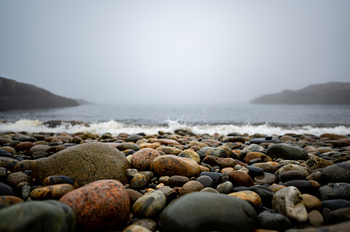 Multi-colored round rocks on Little Hunters Beach in Acadia National Park, Maine. Tide coming in as waves crash. . High quality photo