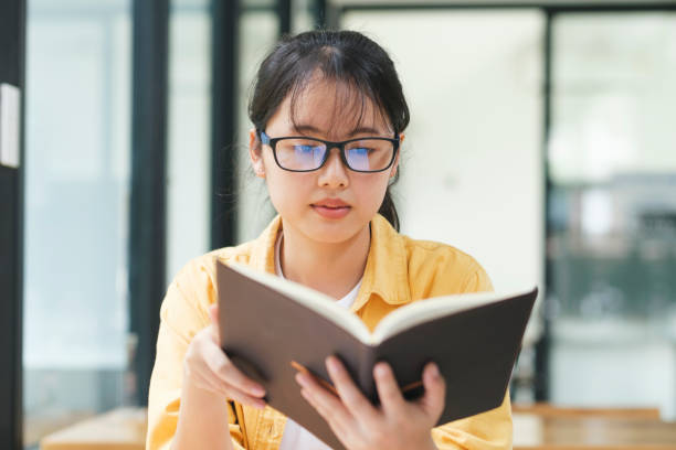 istock Serious young asian student reading a book preparing the exam. 1425742104