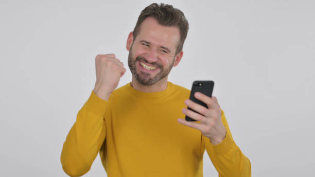 istock Middle Aged Man Celebrating on Smartphone, White Background 1425751191