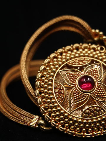 women's antique necklace that comes with a gold pendant with a red orb jewel and a golden chain isolated in a black background