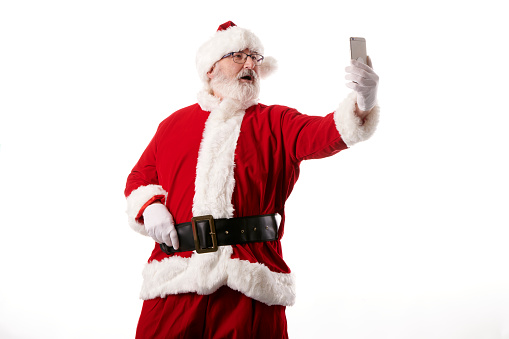 Santa Claus taking a selfie with a mobile phone on a white background