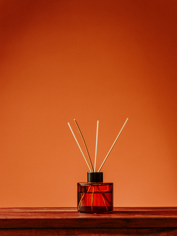 essential oils in glass diffuser in studio orange background still life