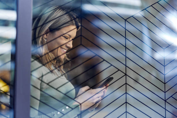 istock Happy woman using mobile phone by the window. 1425763199
