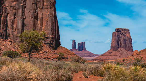 Towering sand stone buttes seen at Monument Valley during a crisp and fresh summer day with blue sky and light clouds. Located on the Arizona and Utah border, USA.