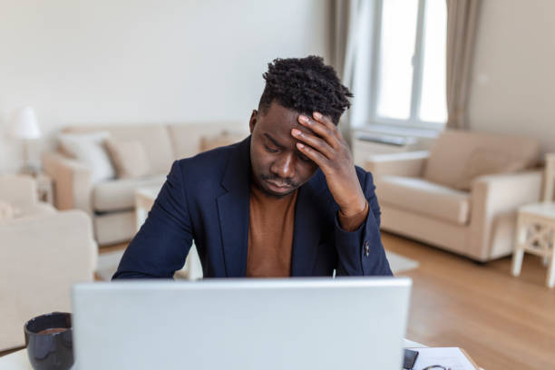 istock Head shot stressed young african american man touching forehead, suffering from terrible headache, working on computer at home office. Frustrated confused biracial guy having painful feelings in head. 1425771668