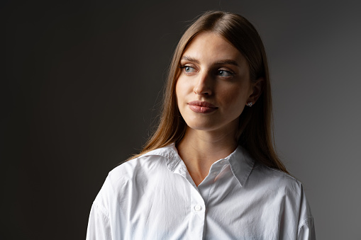 Thoughtful businesswoman portrait on a dark gray background close up