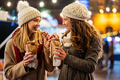 Happy women friends enjoying christmas market and having fun together outdoors.