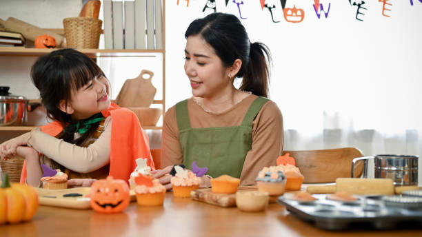 istock Playful young Asian girl laughing and playing with her mom while making Halloween cupcakes 1425784868