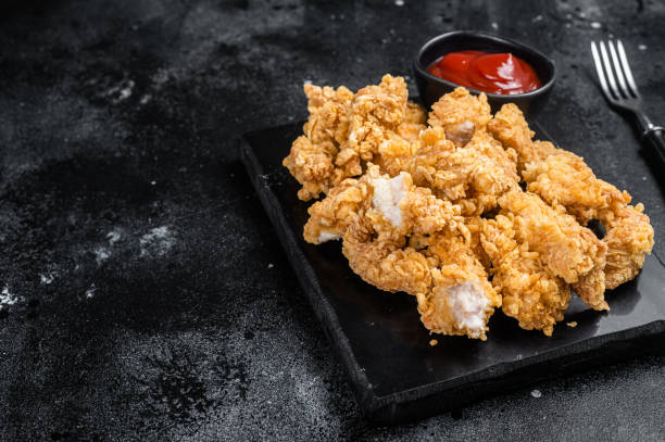 istock Crispy Fried breadcrumb covered chicken popcorn with ketchup. Black background. Top view. Copy space 1425788014