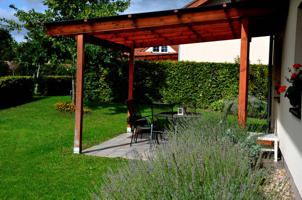 terrace with wooden pergola and plexiglass roof. vines are straining, crawling under the beams. garden or park. sitting with dry wall wine region. restaurant countryside france terrace with wooden pergola and plexiglass roof. vines are straining, crawling under the beams. garden or park. sitting with dry wall wine region. restaurant countryside france, creeper, lavandula, vinifera wet wood texture stock pictures, royalty-free photos & images