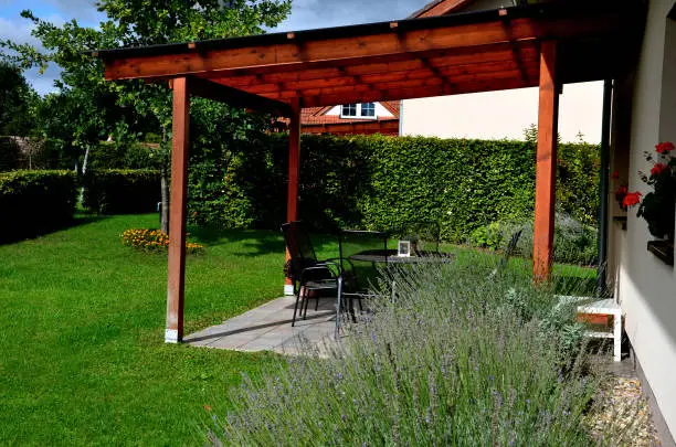 terrace with wooden pergola and plexiglass roof. vines are straining, crawling under the beams. garden or park. sitting with dry wall wine region. restaurant countryside france, creeper, lavandula, vinifera