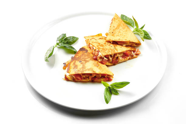 Quesadilla with tomatoes and cheese in a white plate. Close-up, selective focus. White background. stock photo