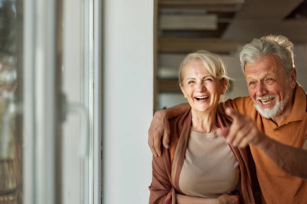 istock Cheerful senior couple looking through window at home. 1425795905