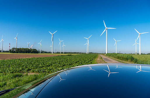 Windpark in the Netherlands with  reflection in a car roof on a sunny day with a clear sky.