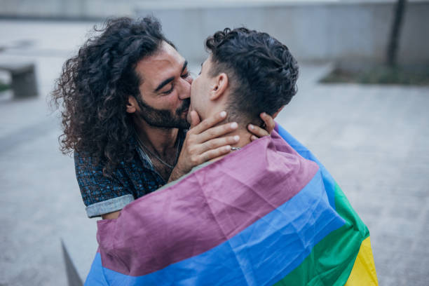 istock Gay couple wrapped in rainbow flag hugging 1425805902