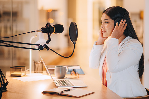 Podcast studio, woman and checking headphones for broadcast media entertainment preparation. Digital audio influencer girl doing sound test of technology equipment and recording gear for show.