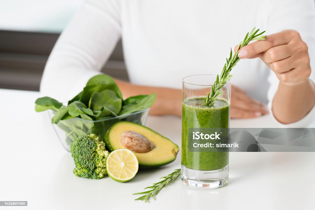 Wheatgrass Smoothie A bundle of wheatgrass, avocado , lemon and micro greens with a green smoothie on desk in kitchen. Magnesium Stock Photo
