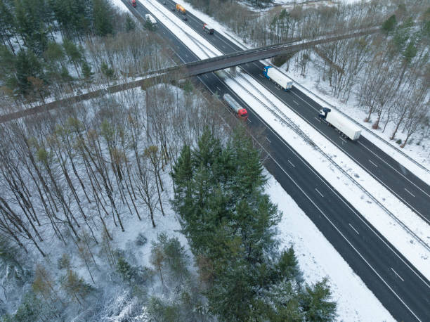 autopista a través de un paisaje de bosque nevado visto desde arriba - highway traffic aerial view netherlands fotografías e imágenes de stock